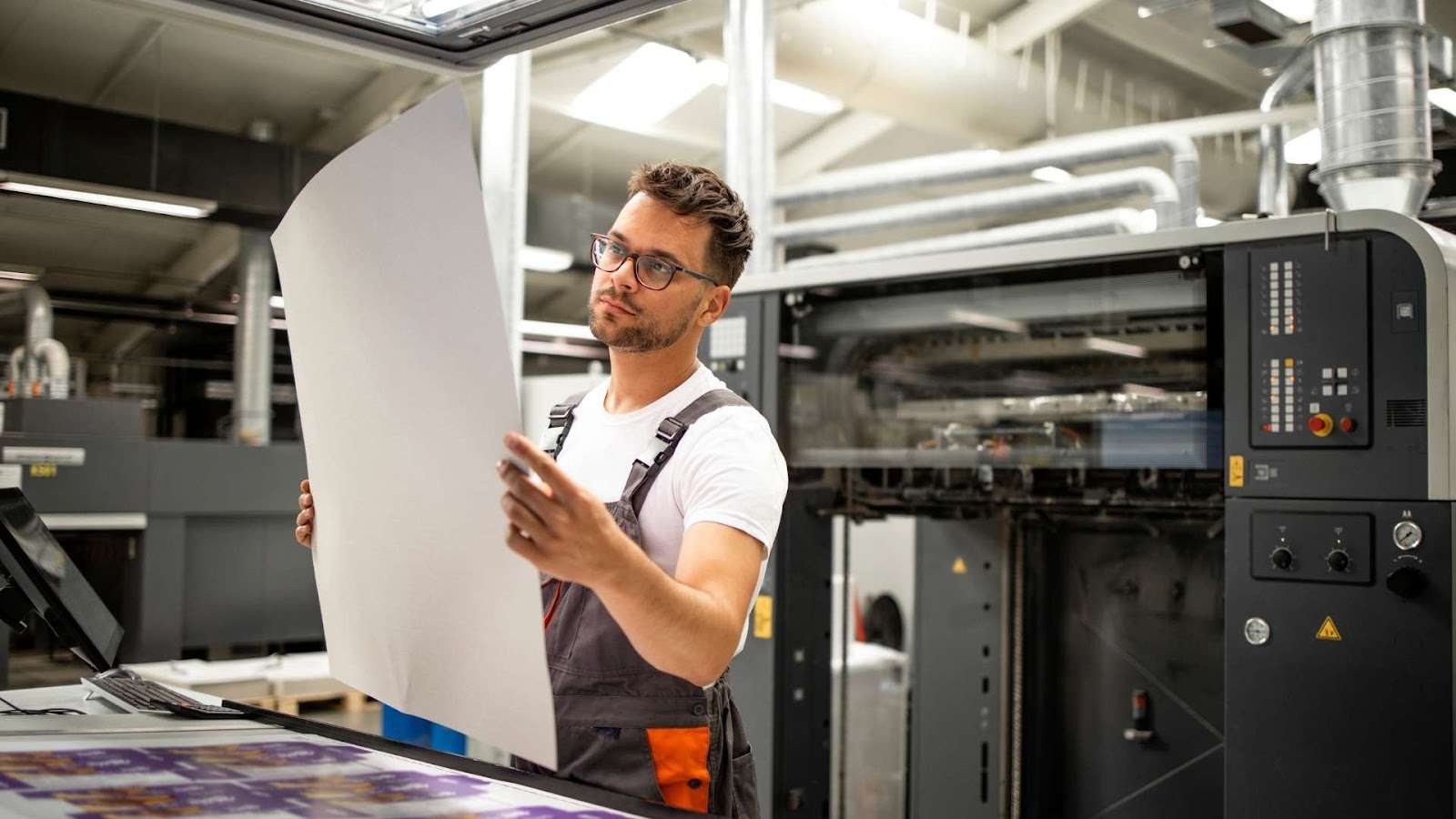 An industrial offset printing press in operation, producing high-volume business brochures with precision and consistent color quality.