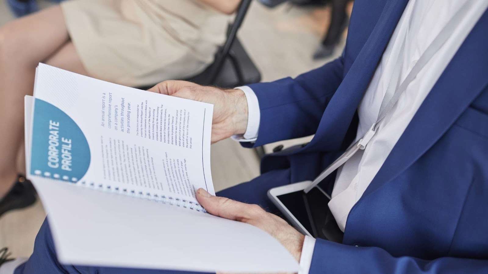 A businessman holding an open spiral-bound corporate instructional manual, showcasing professional layout and clear typography on high-quality printed pages.