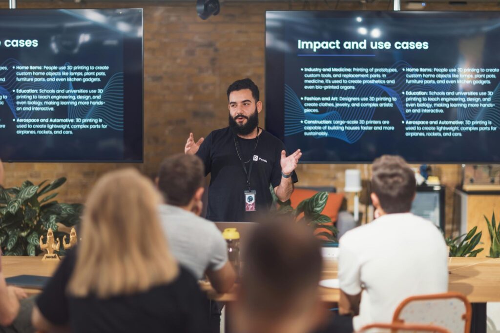 Corporate event presenter speaking to seated audience in modern conference room with presentation screens — event printing for corporate events by Print It ZA