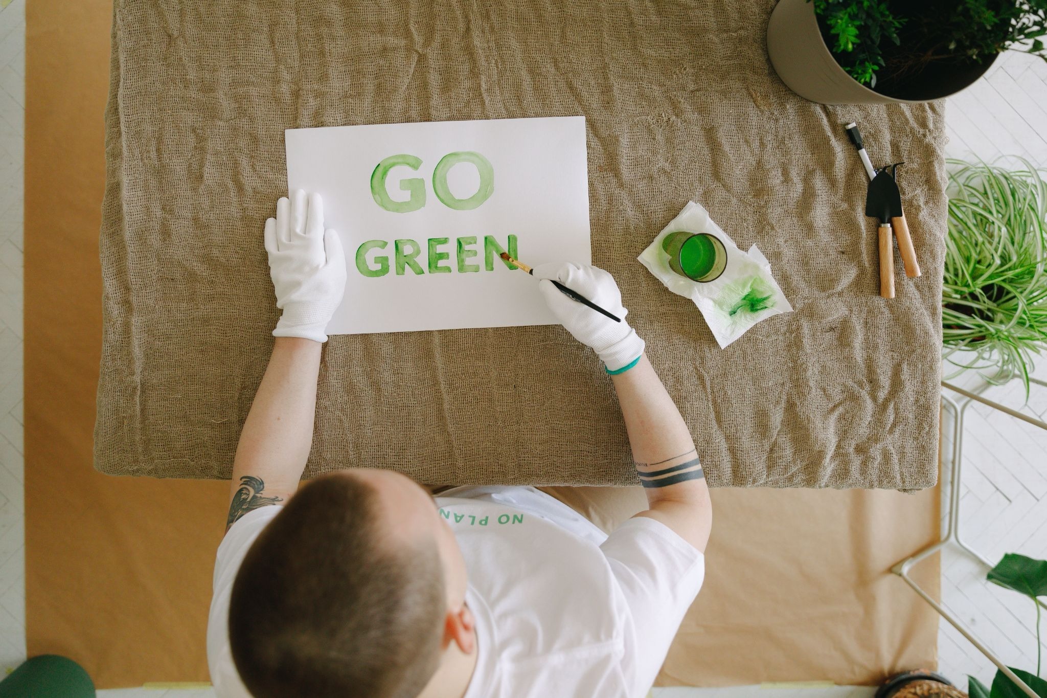 Person painting a "Go Green" sign, symbolising eco-friendly printing for South African brands